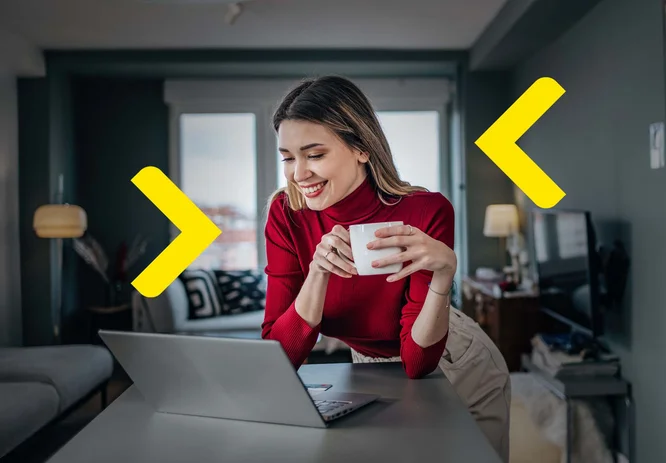 The image shows a woman standing by a desk, holding a cup. In front of her is a laptop, and bright windows with a city view are visible in the background. The interior is modern, featuring warm lighting and stylish furniture, creating a cozy atmosphere. The woman is wearing a red blouse, which adds color to the overall composition.