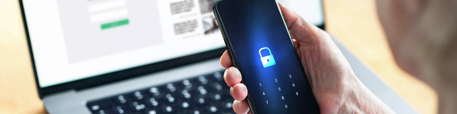 Ręka trzymająca smartfon z ekranem wyświetlającym ikonę kłódki,.