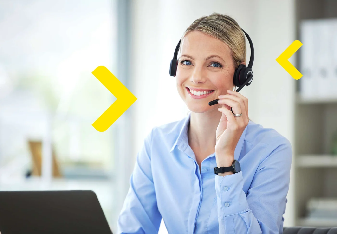 Kobieta pracująca w call center siedzi przy biurku ze słuchawkami na głowie.