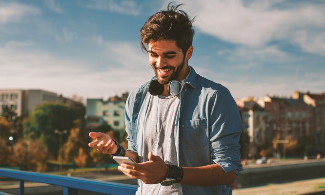 Young happy man using a smartphone  in the city