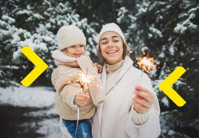 Kobieta ciepło ubrana siedzi na ławce w parku w jesiennej aurze i uśmiecha się do telefonu