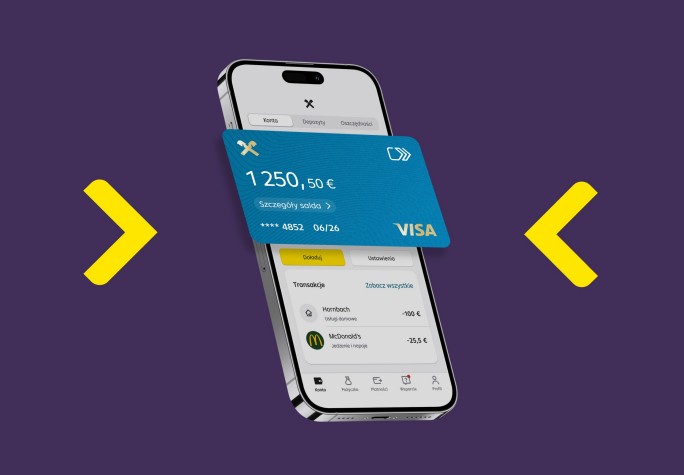 Osoba trzyma smartfon i korzysta z aplikacji, na której wyświetlają się informacje finansowe. W tle widać psa leżącego na podłodze. Ujęcie przedstawia domowe, przytulne otoczenie.