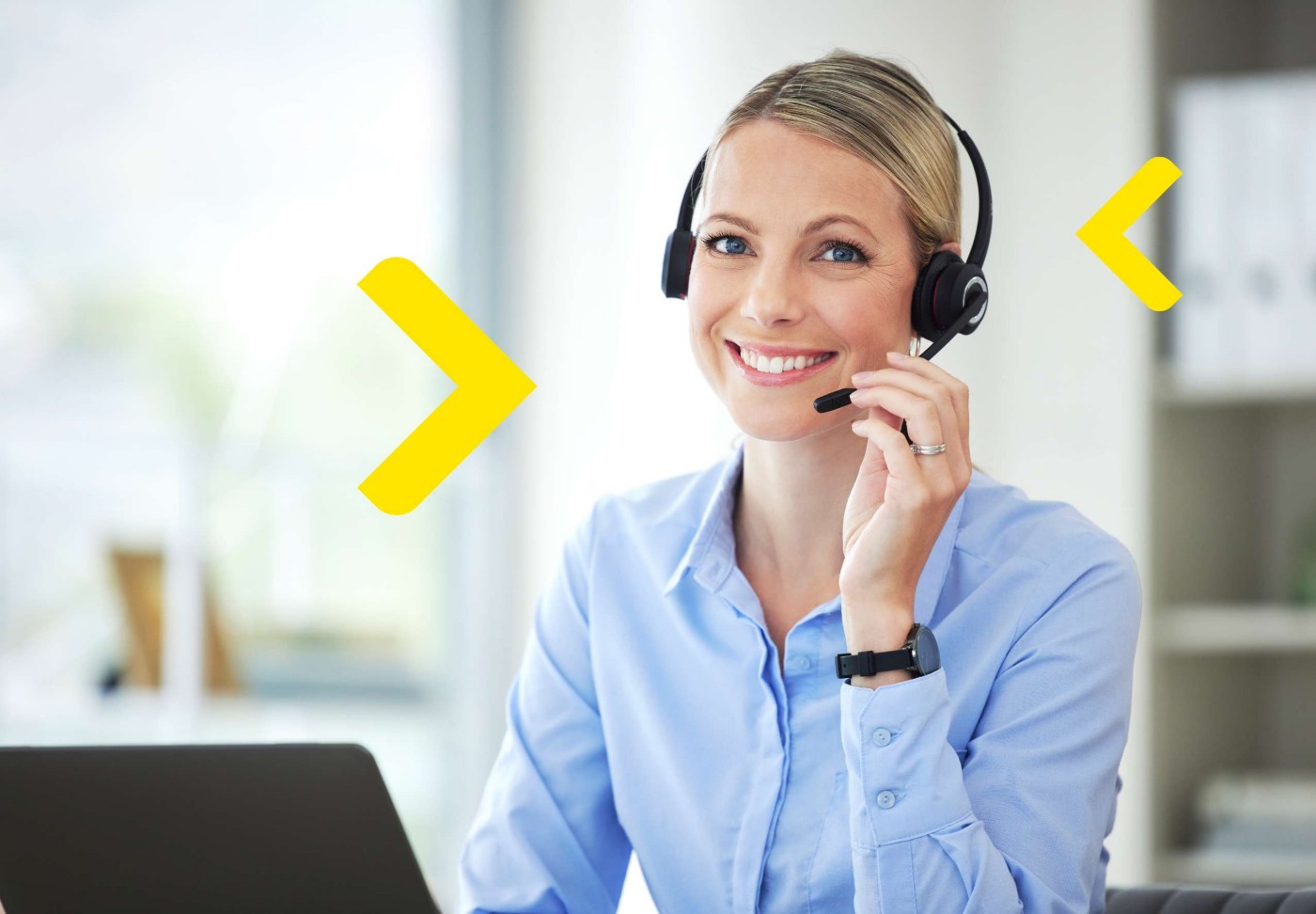 Kobieta pracująca w call center siedzi przy biurku ze słuchawkami na głowie.