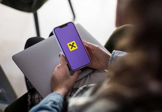 Zdjęcie przedstawia korzystanie z usług Raiffeisen  Digital Banku na urządzeniu mobilnym, podkreślając innowacyjność, bezpieczeństwo i dostępność bankowości cyfrowej.
