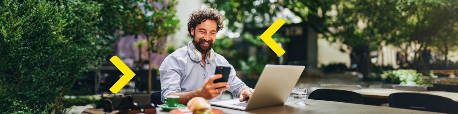 Obrazek ilustrujący nowoczesną bankowość cyfrową Raiffeisen, przedstawiający osobę korzystającą z laptopa i smartfona w przyjemnym otoczeniu. Grafika podkreśla wygodę i elastyczność korzystania z usług bankowych online, umożliwiając zarządzanie finansami w dowolnym miejscu.