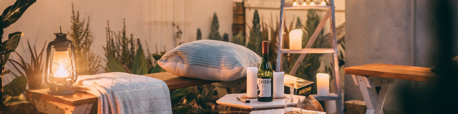 Zdjęcie przedstawia sypialnię z łóżkiem, dekoracyjnymi poduszkami i roślinami. Wnętrze jest jasne i przyjazne, zapewniając komfort