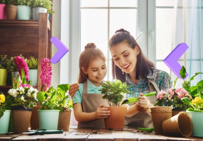 Matka z dziewczynką sadzące rośliny w doniczkach na stole, otoczone kwiatami i zielenią, w jasnym pomieszczeniu z dużym oknem